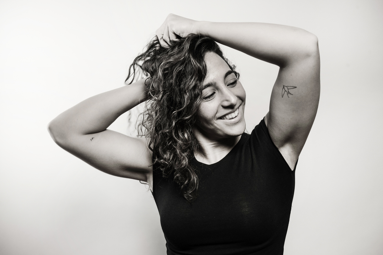 Smiling client with curly hair lifting her arms, embracing a fresh start